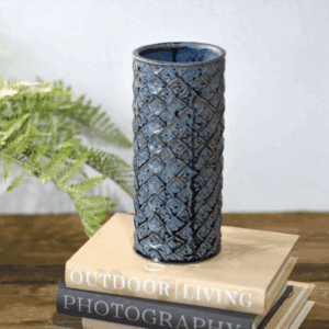 Tall blue ceramic vase with textured pattern on books.
